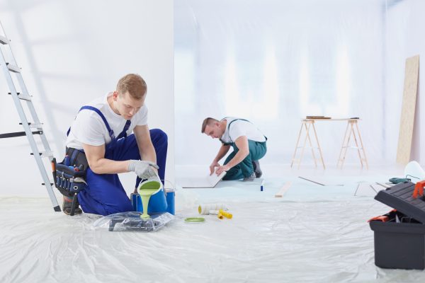 Two young painters are painting the wall in the room